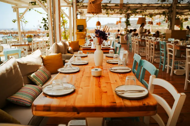 A long wooden table laid for lunch on a shaded terrace