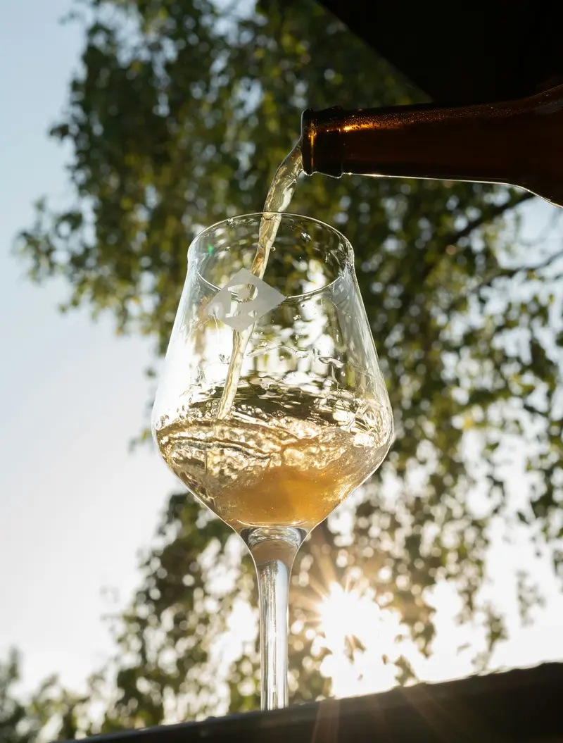 White wine being poured into a glass outdoors