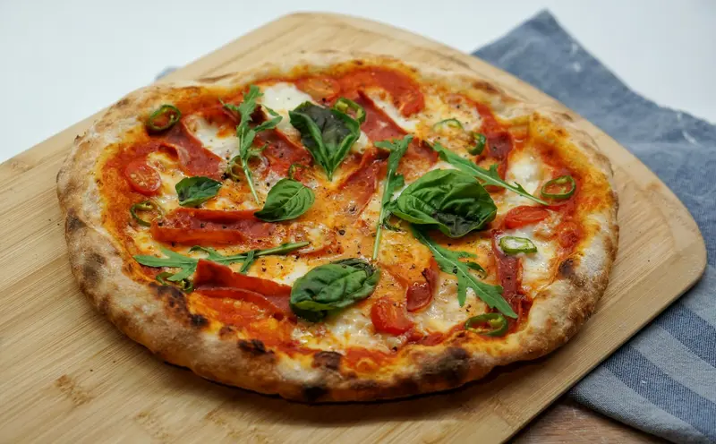 A whole pizza with tomato, mozzarella and basil on a wooden board