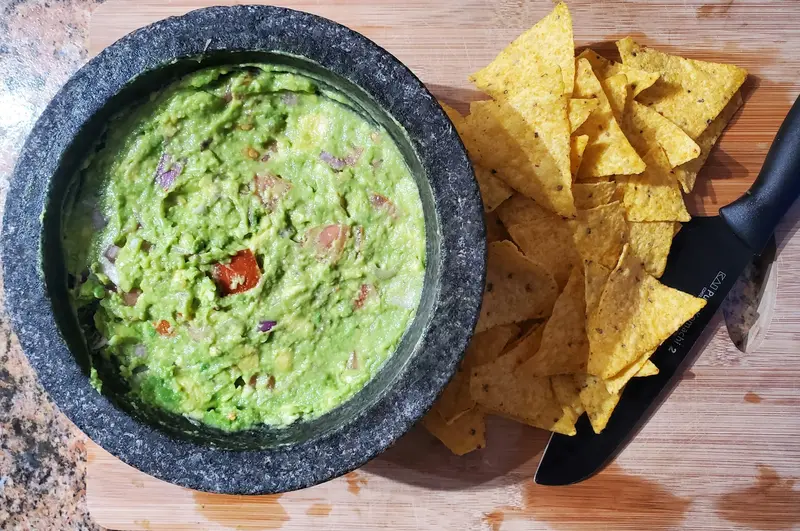A bowl of guacamole with tortilla chips